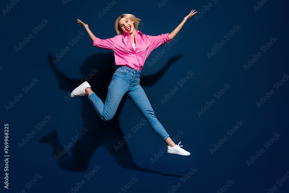 Full length photo of lovely young lady jumping have fun running dressed stylish pink garment isolated on dark blue color background Full length photo of lovely young lady jumping have fun running dressed stylish pink garment isolated on dark blue color background