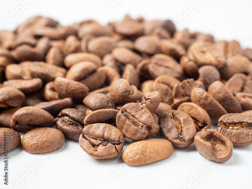 close-up of roasted arabica coffee beans lie on a white background.