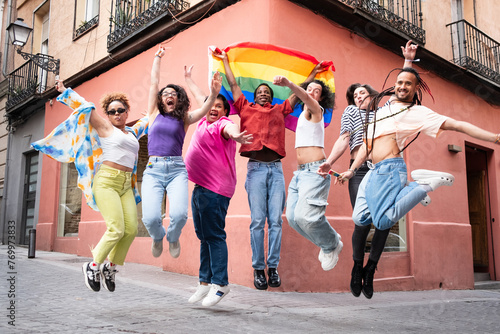 A group of people are jumping in the air and holding a rainbow flag