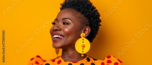  An African-American woman in a yellow polka-dot dress, smiling and facing away from the camera, set on a yellow background