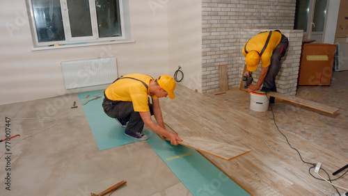 Workers lay laminate flooring in a new home. Internal repair works.