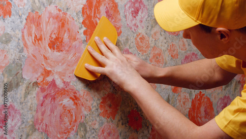 Builder smooths the wallpaper with a spatula. Repair in the house. © DenisProduction.com