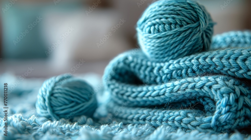 A ball of yarn sits atop a stack of blue crocheted yarn on a bed A ball of yarn sits atop a stack of blue crocheted yarn on a bed
