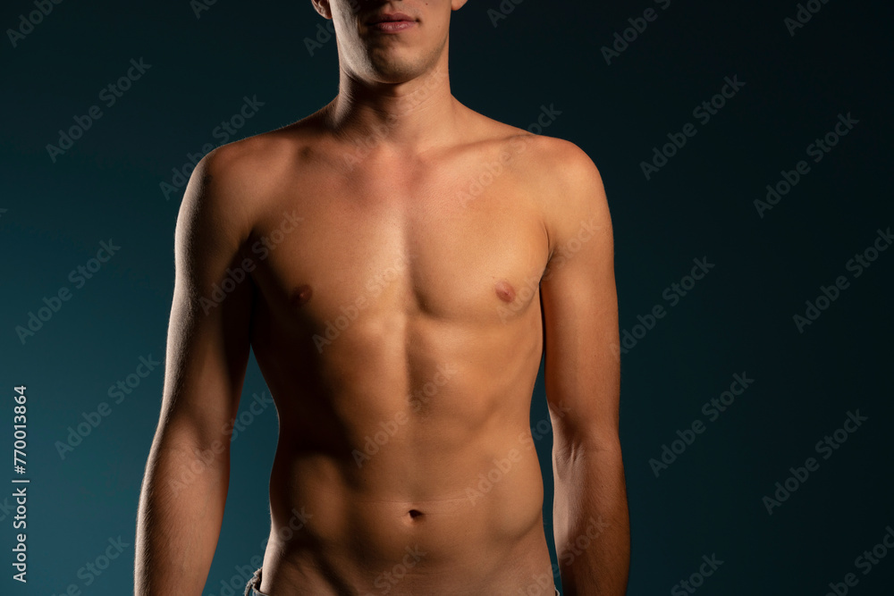 the torso of a young athletic guy. concept: the male body after exercise and diet. men's health: shaved breasts on a dark background the torso of a young athletic guy. concept: the male body after exercise and diet. men's health: shaved breasts on a dark background