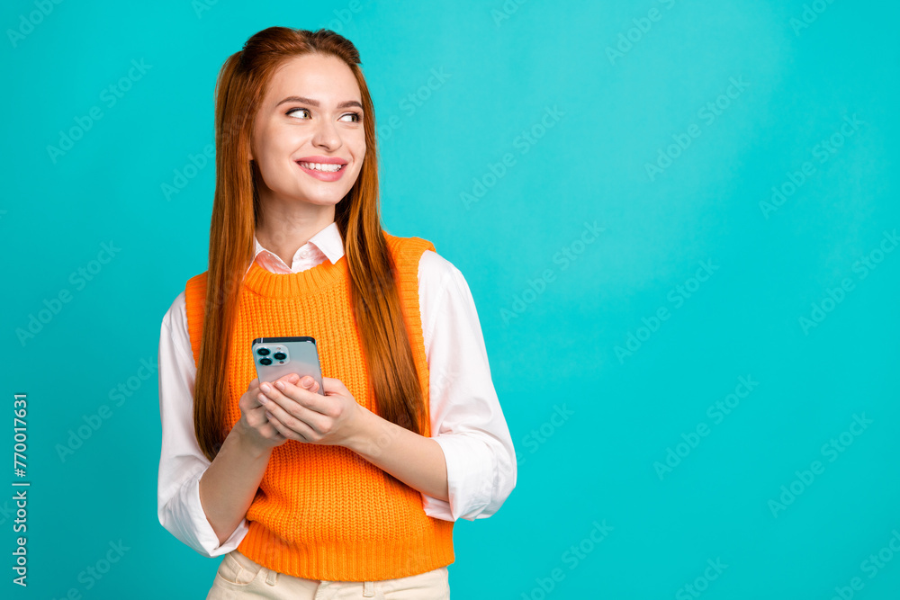 Photo of lovely adorable pretty girl wear stylish orange clothes hold device look empty space isolated on cyan color background Photo of lovely adorable pretty girl wear stylish orange clothes hold device look empty space isolated on cyan color background