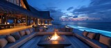 Maldives night haven: Firelit seating seating area oasis with a large fire pit and comfortable loungers amidst modern architectural design luxury villa