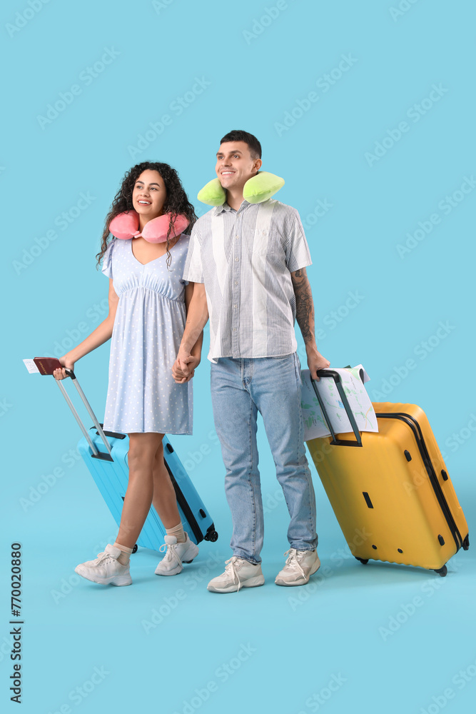 Couple of tourists with suitcases and neck pillows on blue background Couple of tourists with suitcases and neck pillows on blue background