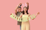 Happy young couple with Easter garland and bunny ears on pink background