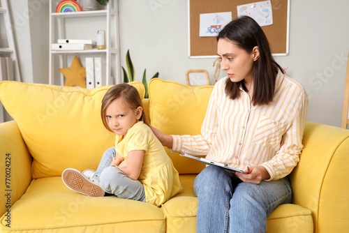 Female psychologist working with sad little girl in office