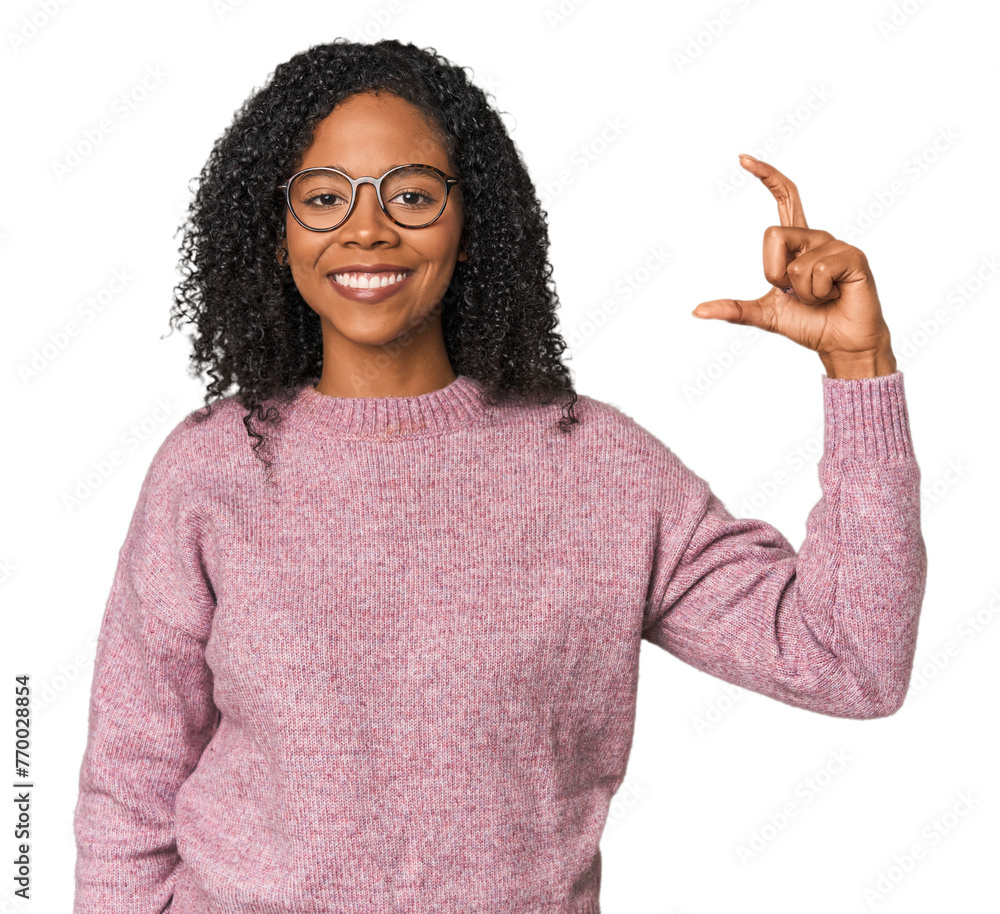 African American woman in studio setting holding something little with forefingers, smiling and confident. African American woman in studio setting holding something little with forefingers, smiling and confident.