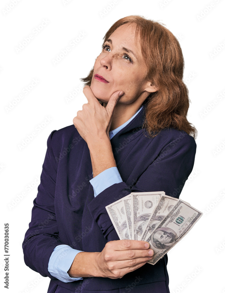 Mid-aged Caucasian with dollars in studio looking sideways with doubtful and skeptical expression. Mid-aged Caucasian with dollars in studio looking sideways with doubtful and skeptical expression.