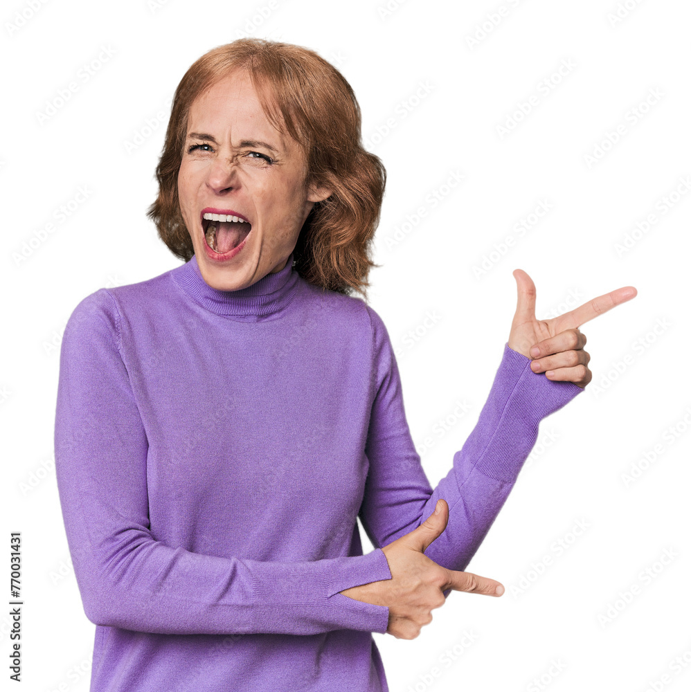 Redhead mid-aged Caucasian woman in studio pointing with forefingers to a copy space, expressing excitement and desire. Redhead mid-aged Caucasian woman in studio pointing with forefingers to a copy space, expressing excitement and desire.