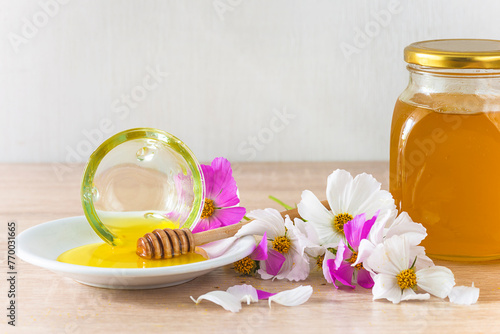 Bowl with honey and heap of flowers on a wooden table photo