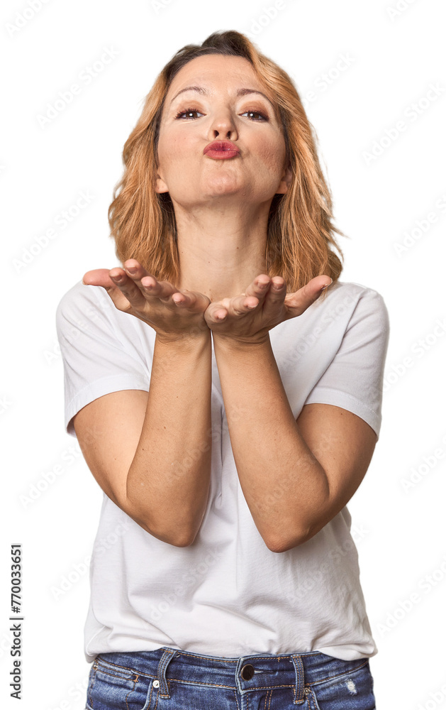 Blonde middle-aged Caucasian woman in studio folding lips and holding palms to send air kiss. Blonde middle-aged Caucasian woman in studio folding lips and holding palms to send air kiss.