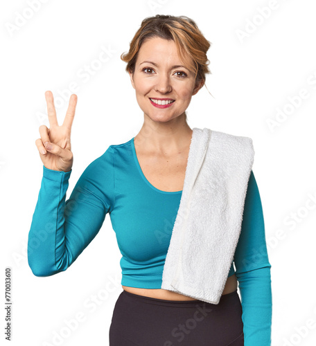 Caucasian woman in sportswear with towel joyful and carefree showing a peace symbol with fingers.