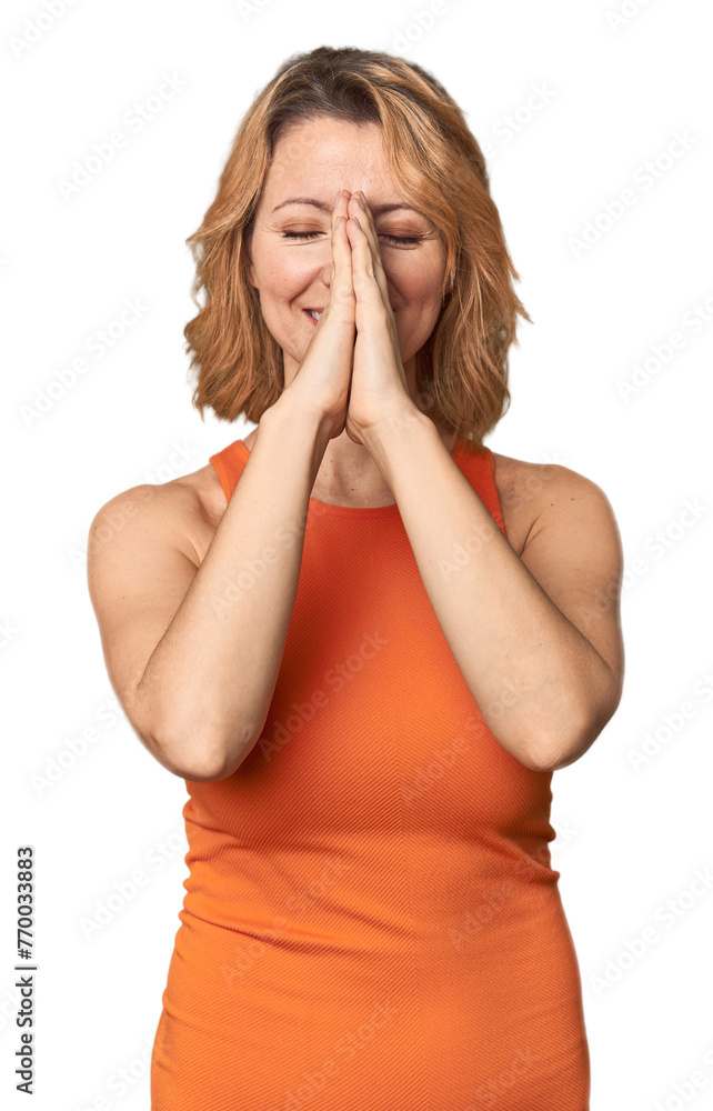 Blonde middle-aged Caucasian woman in studio holding hands in pray near mouth, feels confident. Blonde middle-aged Caucasian woman in studio holding hands in pray near mouth, feels confident.