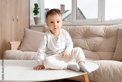 Little boy on table at home. Child in danger
