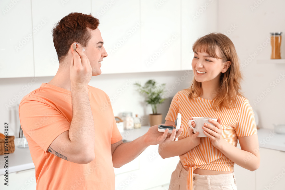 Young deaf mute couple with hearing aid in kitchen Young deaf mute couple with hearing aid in kitchen