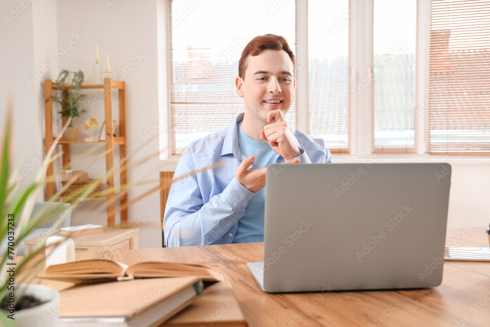 Young deaf mute man video chatting in sign language at home Young deaf mute man video chatting in sign language at home