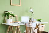 Stylish workplace with lamp, houseplants and laptop in light office
