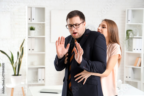 Business woman seducing her male colleague in office. Harassment concept photo