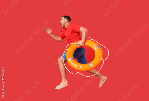 Worried young lifeguard with lifebuoy running on red background