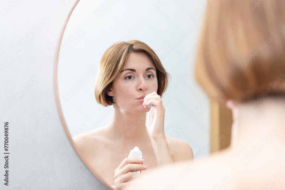 Attractive woman brushing teeth and looking at the mirror in the bathroom Attractive woman brushing teeth and looking at the mirror in the bathroom
