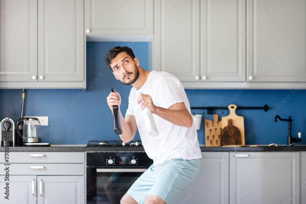 Funny man holding bottle spray and cleaning table. Household and housekeeping concept Funny man holding bottle spray and cleaning table. Household and housekeeping concept