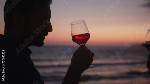 Multiethnic boyfriend and girlfriend drinking wine against beach sunset sky