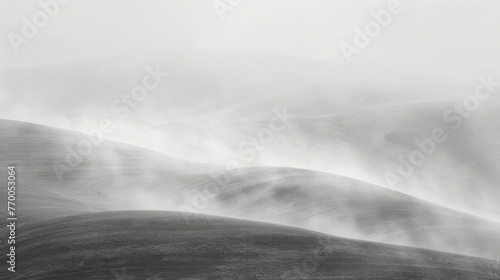  A monochrome image of a rolling landscape featuring hilly terrain in the background and foggy foreground