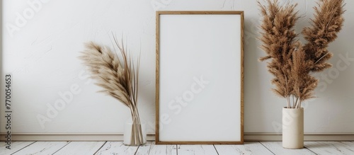 Thin wooden vertical frame mockup, sized 16x20, placed on a white wooden floor alongside a pampas grass prop.