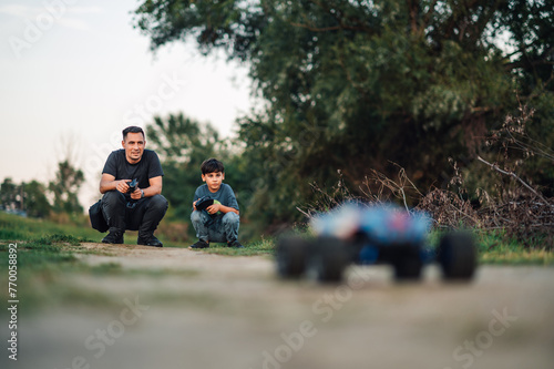 Father and his son crouching while playing with a remote controlled toy car