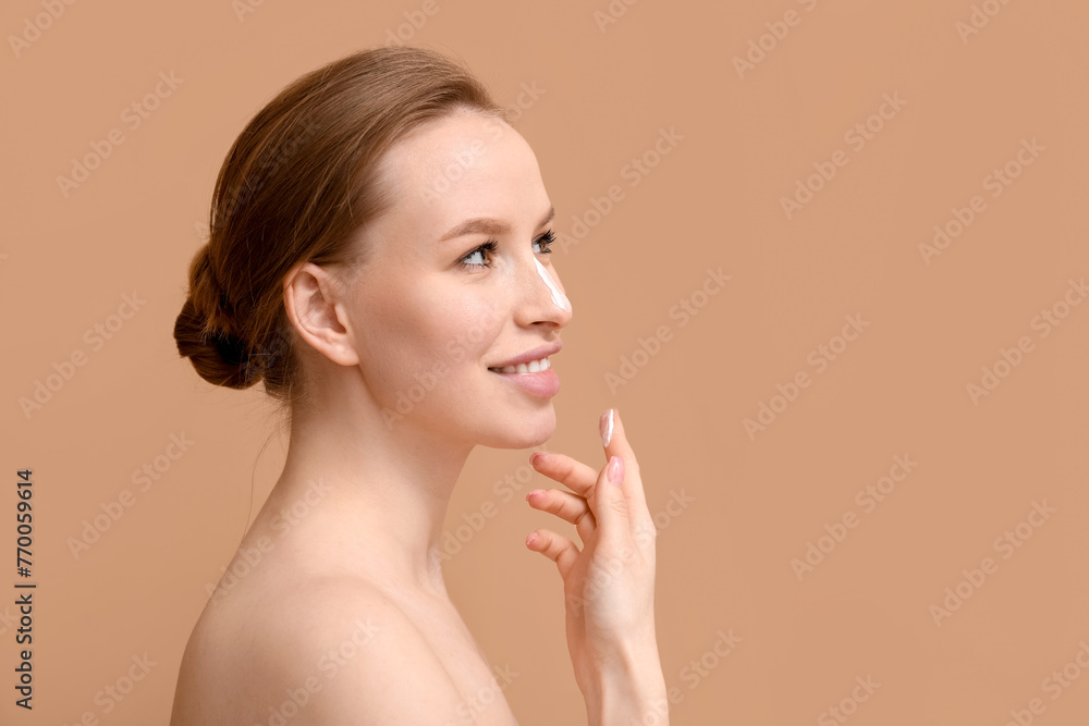 Young woman applying facial cream on brown background Young woman applying facial cream on brown background