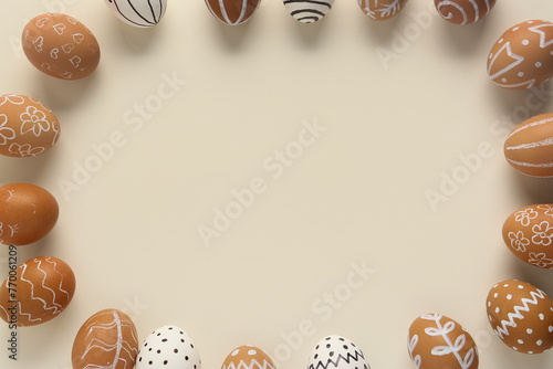 Stylish Easter frame made of painted eggs on beige background, closeup