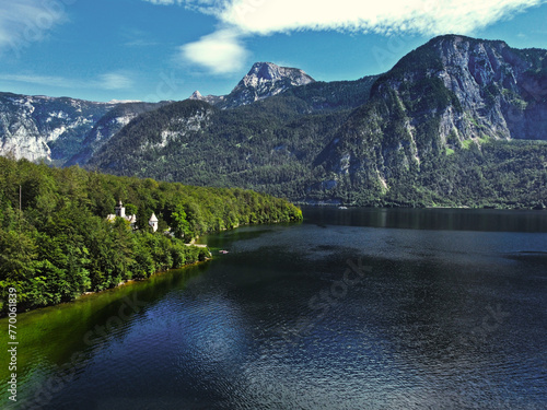 A lake and a mountain with green trees above the lake in the summer and on a beautiful sunny day
