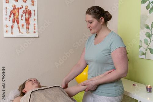 Physiotherapeutin massiert eine weibliche Patientin am Arm