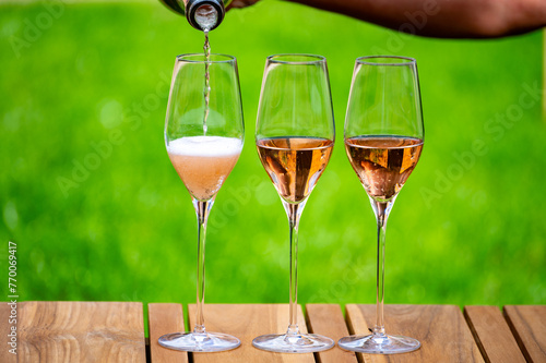 Picnic on green grass with glasses of rose champagne sparkling wine or cava, cremant produced by traditional method in caves in Champagne region, France
