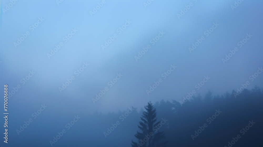 Blurred misty landscape with forest trees. Cold quiet morning among mist-covered woods. Serene and foggy forest scene in cool tones.