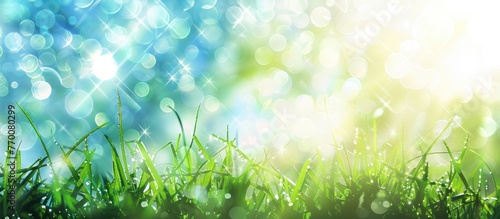 Spring-themed abstract background featuring bokeh effects and sun rays, with grass and a blue sky.
