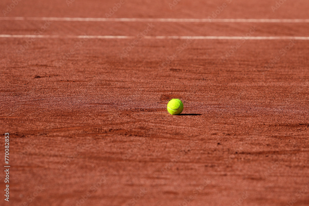 Detail of a tennis ball stopped on the ground of a clay tennis court during a sunny day
