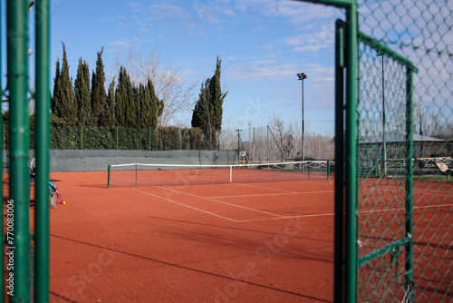Panoramic view from the front door of an empty clay tennis court during a sunny day