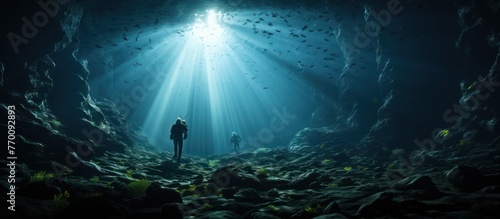 divers pass through a cave at the bottom of the deep sea photo