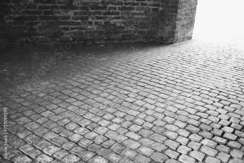 Old cobblestone street with brick wall, monochrome vintage texture. photo