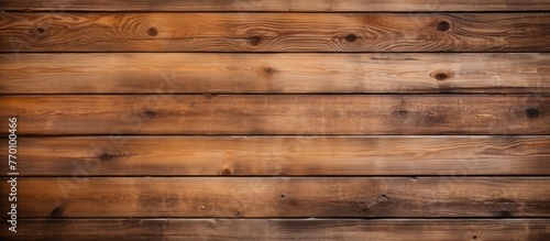 A closeup shot of a brown hardwood plank wall with a blurred background. The wood stain enhances the natural beauty of the lumber, creating a stunning pattern of rectangular tints and shades