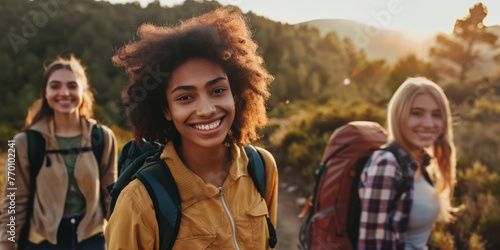 Group of cheerful young friends going hiking together in scenic landscape on spring day. Adventurous young people with backpacks. Hiking and trekking on a nature trail.