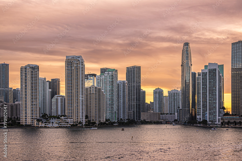 Miami, Florida, USA - July 29, 2023: Sunset red sky over buildings on Brickell Key island N side at evening 19:47 all the way past river mouth. Centinel statue between Tequesta points