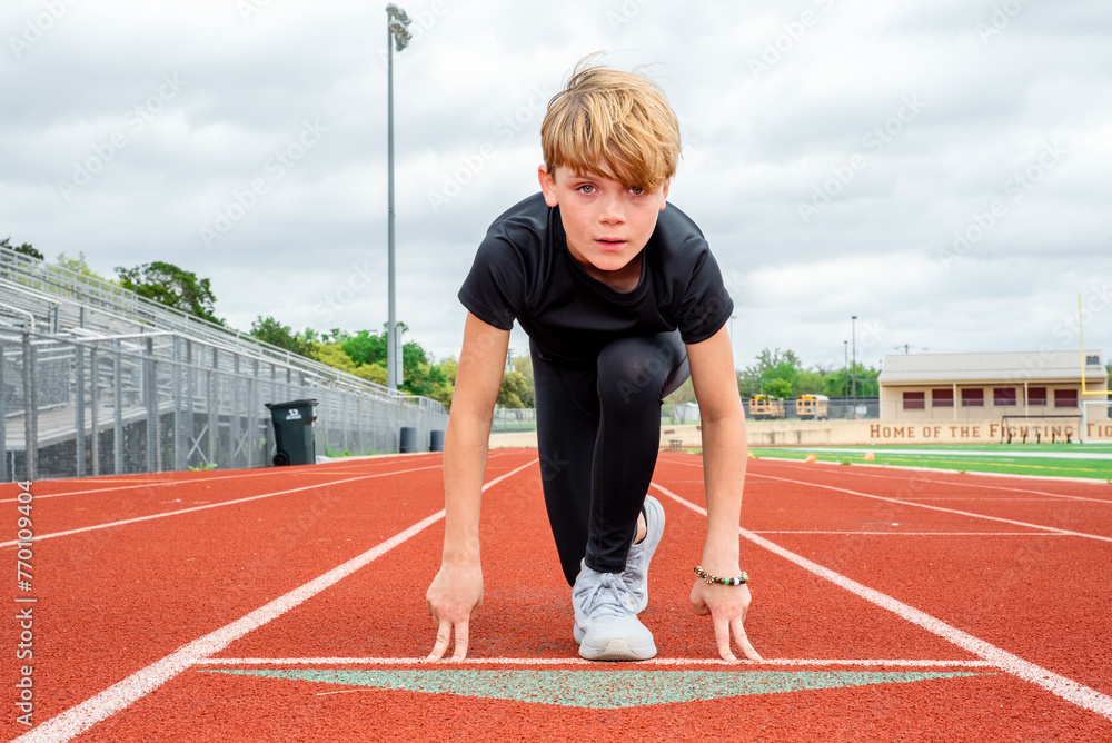 Fototapeta premium Young male track runner in the starting position, head up about to race