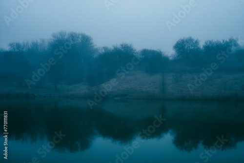 Foggy frost lake . Landscape with fog . Mystery nature . Blue hour . Morning at winter .