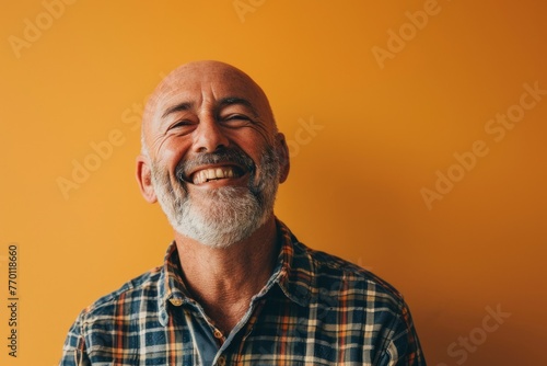 Portrait of a happy senior man on a yellow background. Copy space. © Inigo