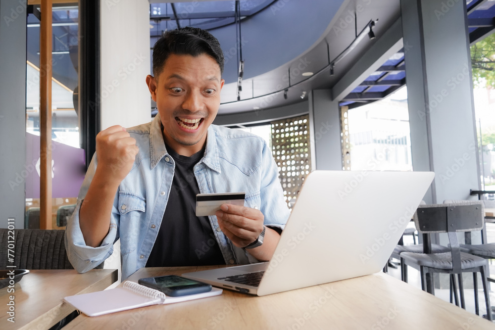 Fototapeta premium Asian man using laptop and mobile phone for shopping online with credit card in coffee shop online freelance business